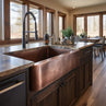 Sinkology hammered copper apron-front kitchen sink installed in dark wood cabinetry with a modern dark faucet.